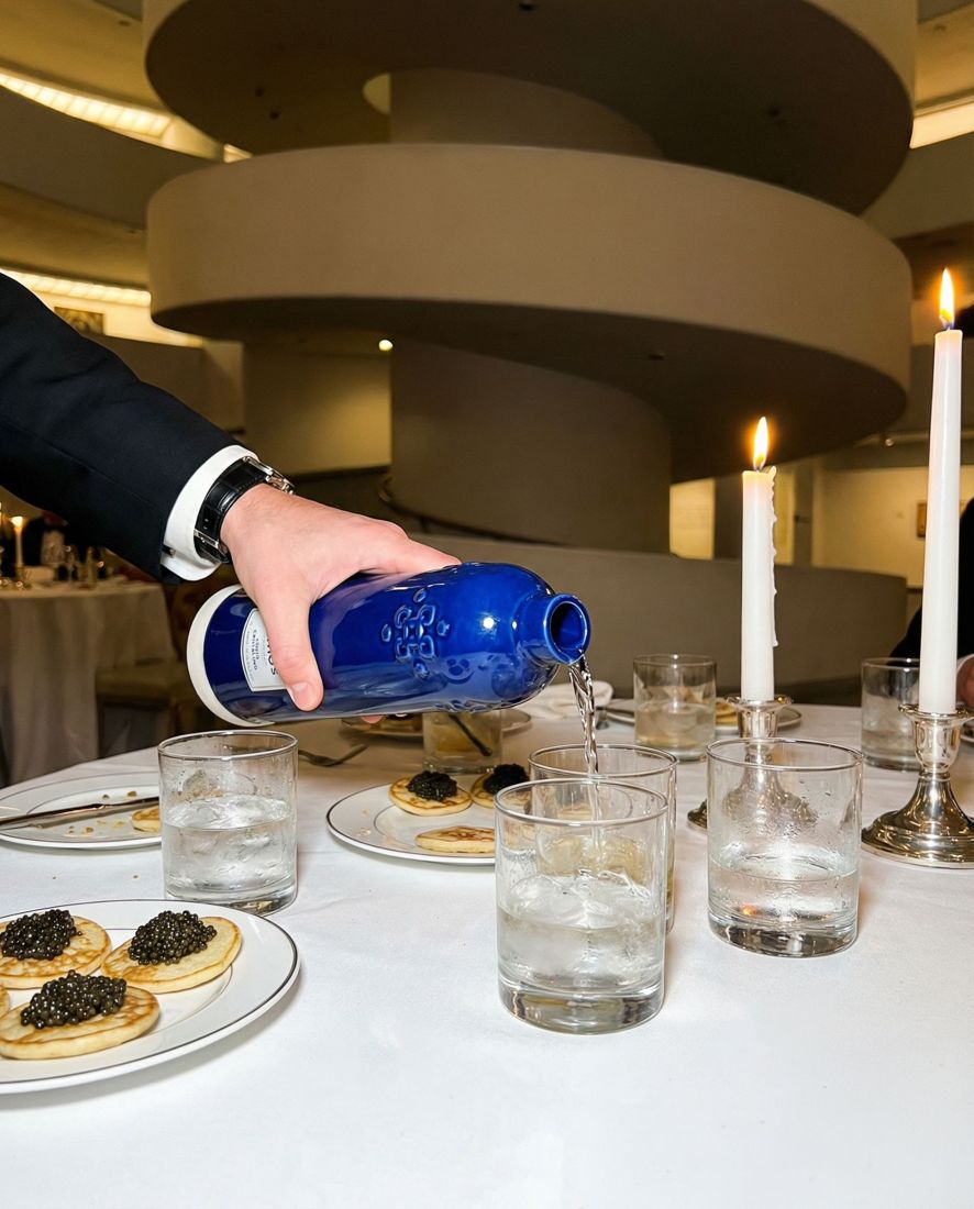 Tequila Komos bottle being poured beside caviar at a candlelit table